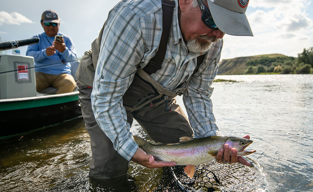 fly fishing landing a trout